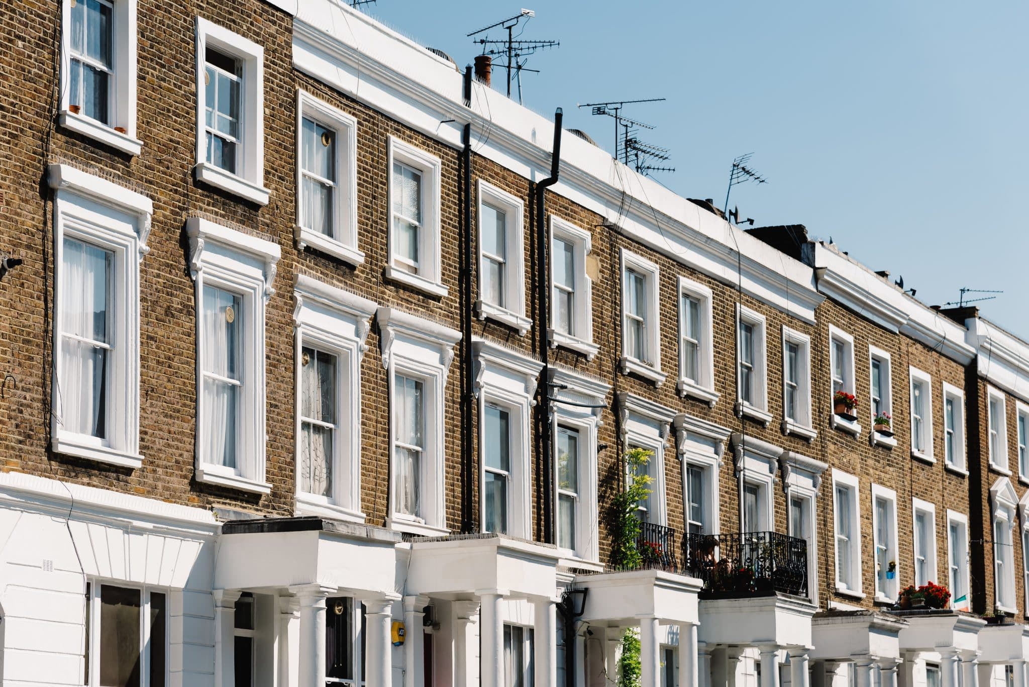 A row of Victorian terraced houses with white stucco porches on a London street